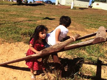 Siblings playing on wooden outdoors play equipment in playground