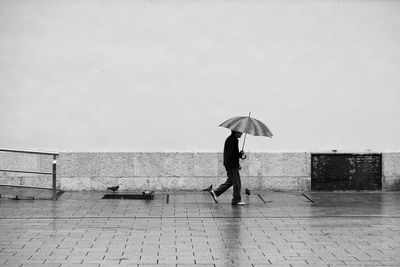 Side view of man walking with umbrella