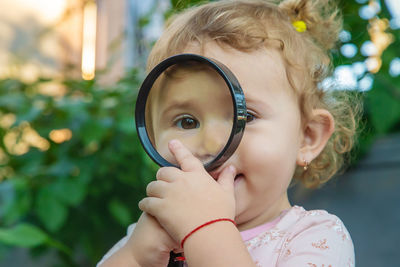 Portrait of young woman holding magnifying glass