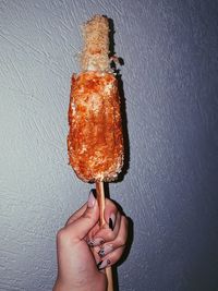 Midsection of person holding ice cream against wall