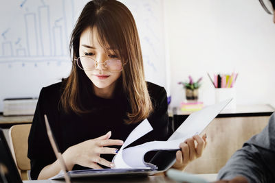 Young woman using phone while sitting on table