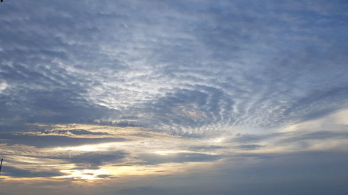 Low angle view of sunlight streaming through clouds