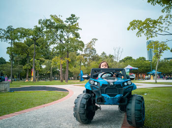 Cute girl sitting in toy car at park