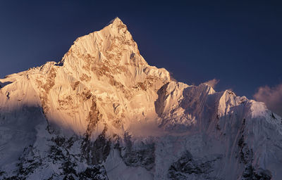 Scenic view of snow covered mountains against blue sky