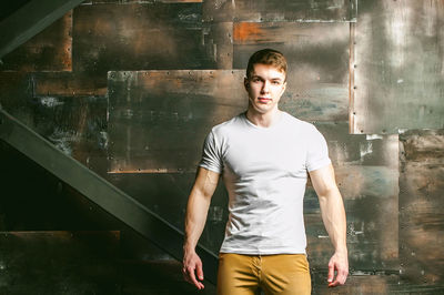 Portrait of muscular man standing by wall