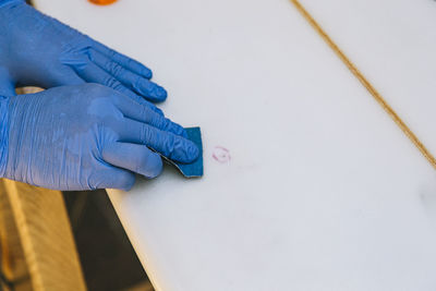 Surfer with protective gloves sanding a repair on the surfboard.