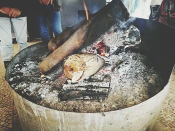 Midsection of people standing by fire pit