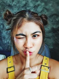 Close-up portrait of young woman winking eye