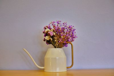 Close-up of flower vase on table against wall