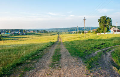 Road amidst field against sky