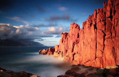 Rock formations by sea against sky during sunset
