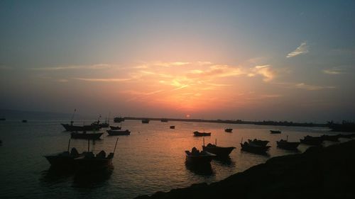 Silhouette boats in sea against sky during sunset