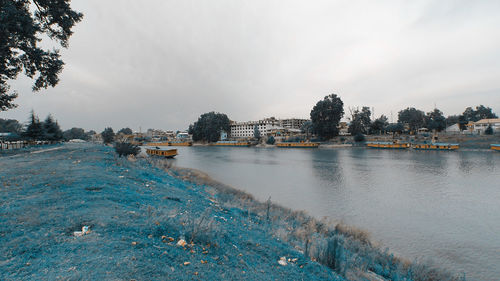 Scenic view of river by buildings against sky