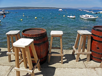 Deck chairs by sea against sky