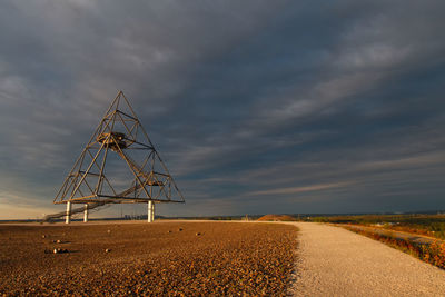 Wind turbines on field by road against sky