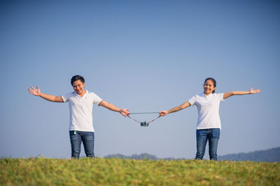 Full length of friends standing on field against clear sky