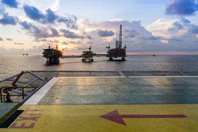 Exit sign on a helipad of a construction work barge with offshore platform on the background