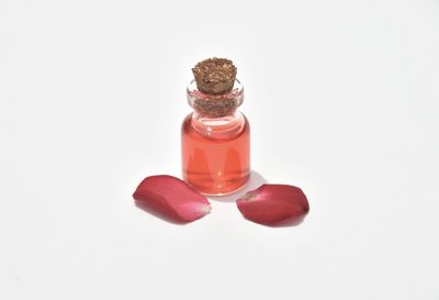 Close-up of red rose in glass bottle against white background