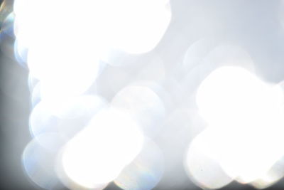 Defocused image of illuminated lights against sky