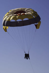 Low angle view of man paragliding against clear sky