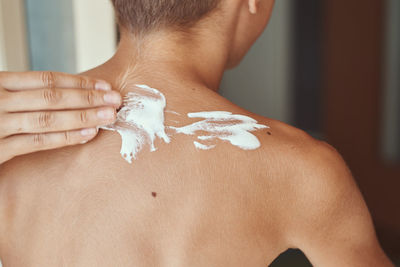 Close-up of woman applying cream on man back