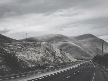 Road leading towards mountain against sky