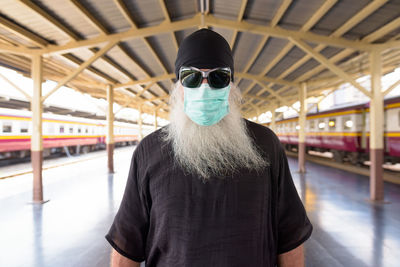 Portrait of man wearing mask at railroad station