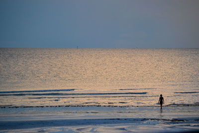 Man walking on beach against clear sky