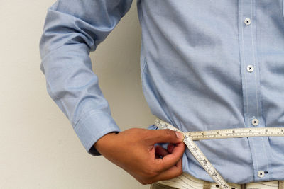 Midsection of man measuring stomach