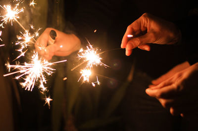 Young woman holding sparkler at night