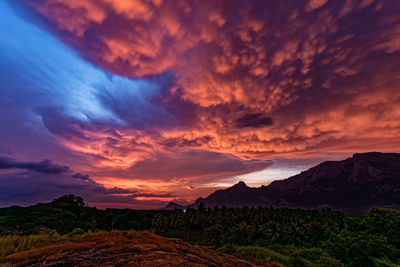 Scenic view of landscape against dramatic sky during sunset