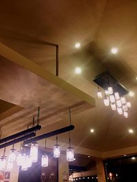 Low angle view of illuminated pendant lights hanging on ceiling