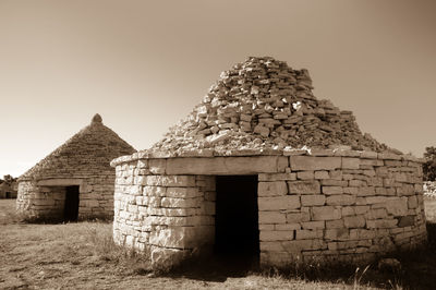 Old stone house on field against clear sky