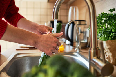 Cropped image of man washing hands in sink