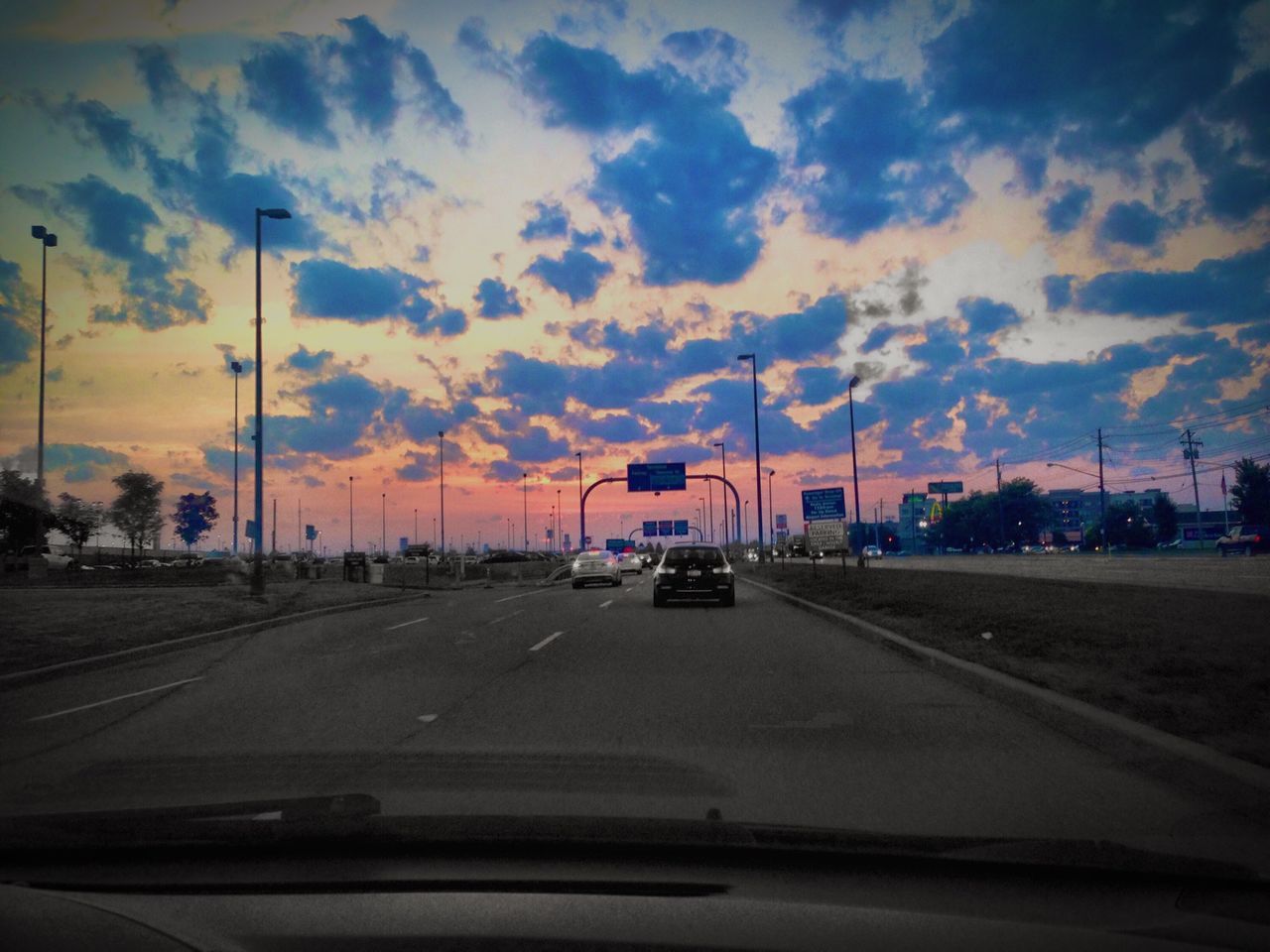 transportation, car, land vehicle, mode of transport, road, sky, on the move, sunset, street, road marking, cloud - sky, travel, the way forward, windshield, street light, vehicle interior, traffic, vehicle, cloud, car interior