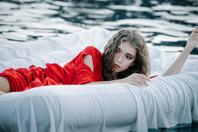 Teenage girl lying down on bed over sea