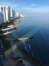 Aerial view of buildings by sea against sky