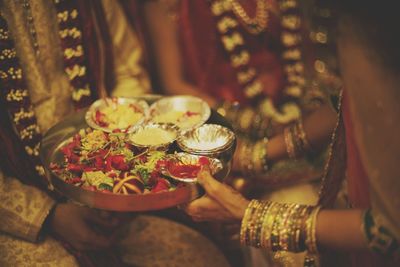 Midsection of woman holding religious offering by bride and groom during wedding