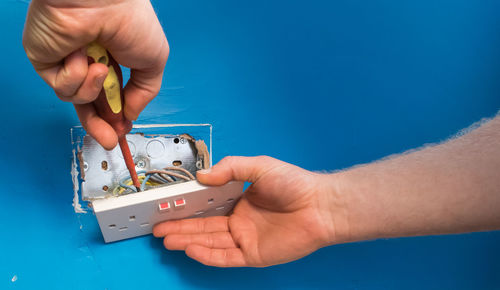 Close-up of electrician fixing socket on wall