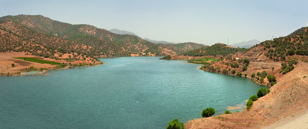 The view of water in a lake with mountains surrounded with clear blue sky, kurdistan province, iran