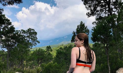 Woman amidst trees against sky