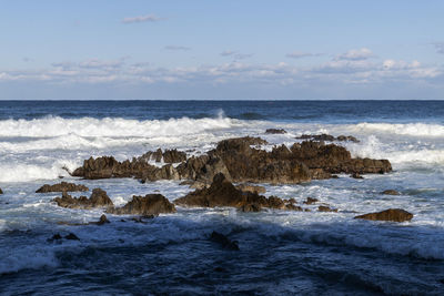 Scenic view of rocks in sea against sky