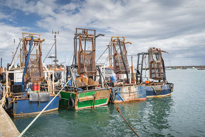 Four small fishing boats with shellfish cages moored in howth harbour, dublin, ireland