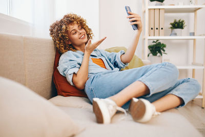 Portrait of young woman sitting on bed at home