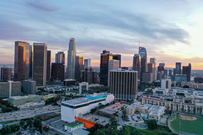 Modern buildings in city against sky during sunset