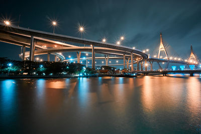 Low angle view of illuminated bridges by lake against sky at night