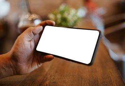 Close-up of hand holding smart phone on table