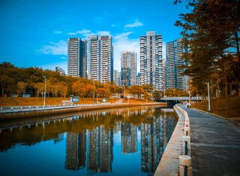 Reflection of buildings in river against blue sky