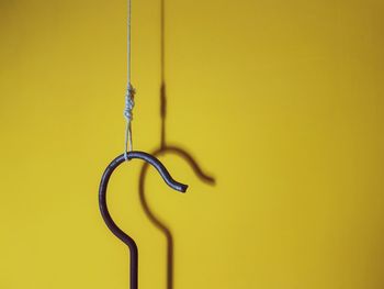 Close-up of metal hanging against yellow wall