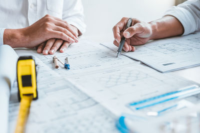 Midsection of man working on blueprint